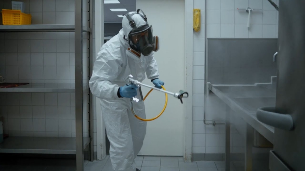 User disinfecting with spray in an industrial kitchen